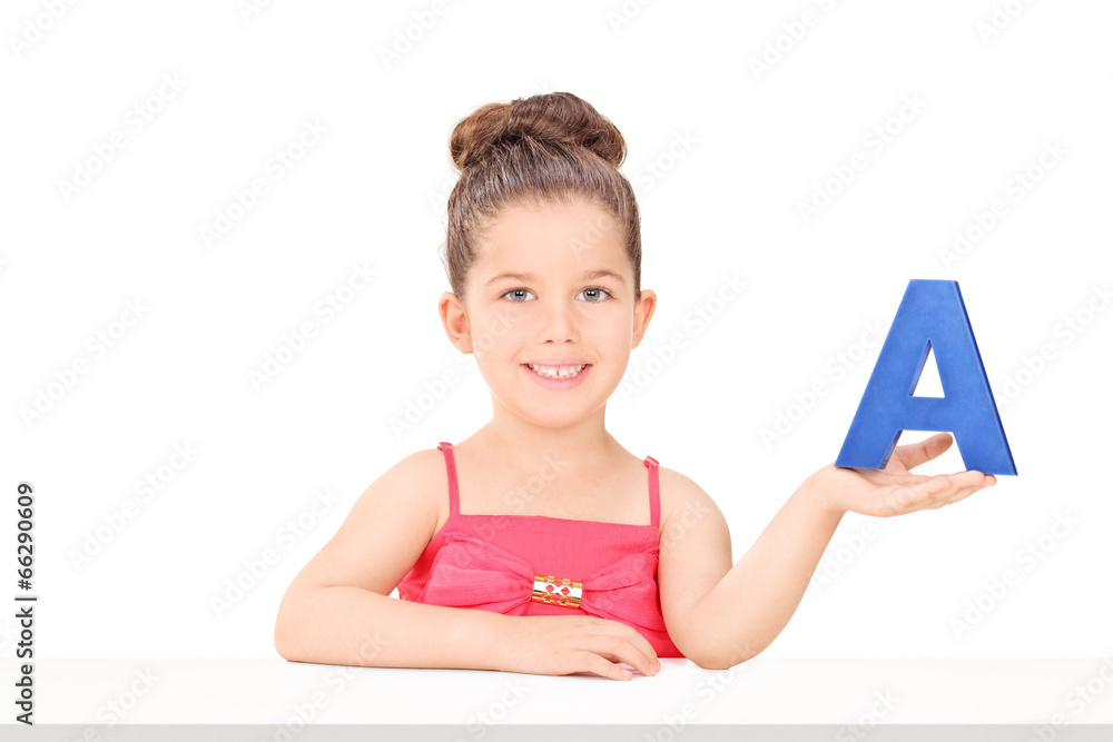 Little girl holding the letter a seated at a table Little girl holding the letter a seated at a table