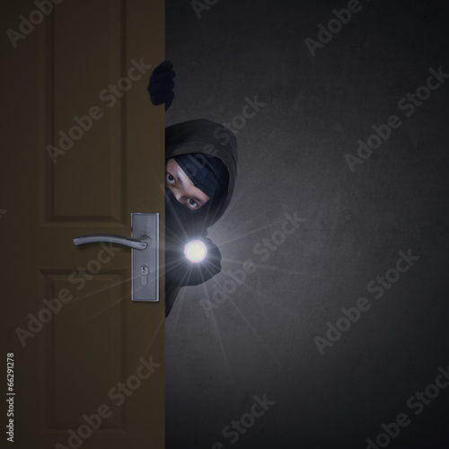 Thief sneaking through door photo