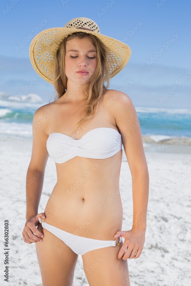 Beautiful blonde on the beach in white bikini and sunhat