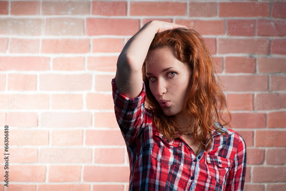 Red haired girl posing against red brick wall Red haired girl posing against red brick wall