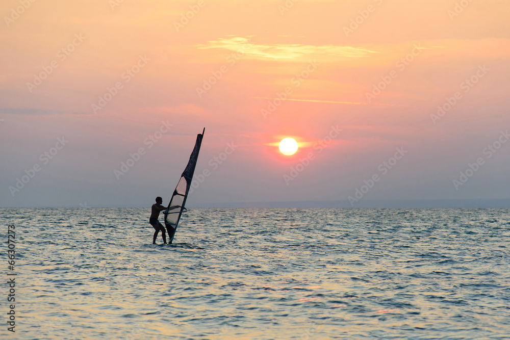 Naklejka premium windsurfer silhouette against sunset background