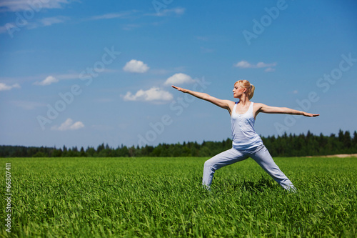 Beautiful healthy young woman doing yoga exercise on field. Yoga