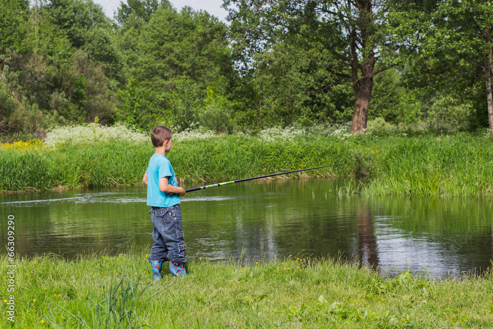 boy with a fishing rod on the river bank