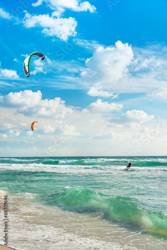 Kitesurfing. Kitesurfers rides the waves against sky.