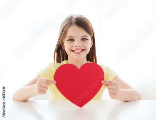 smiling little girl with red heart at home