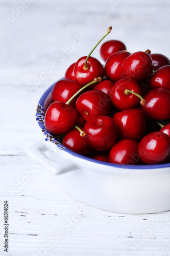 Sweet cherries in color bowl on wooden background