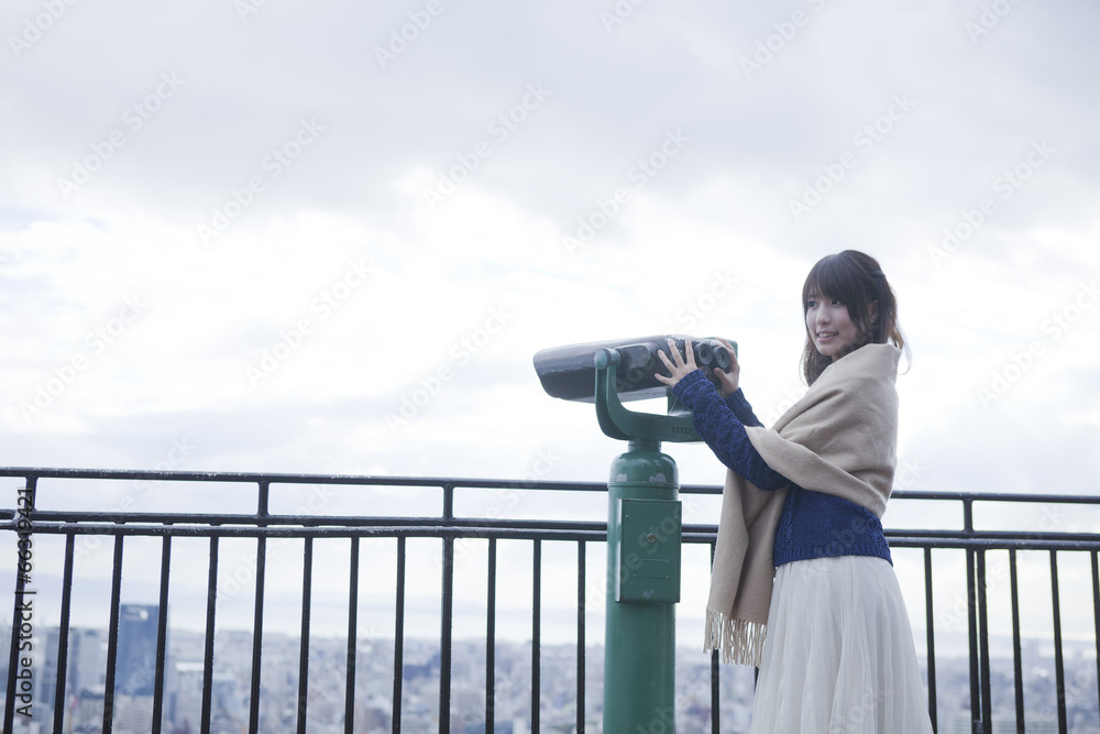 展望台から双眼鏡で神戸の景色を望む笑顔の女性