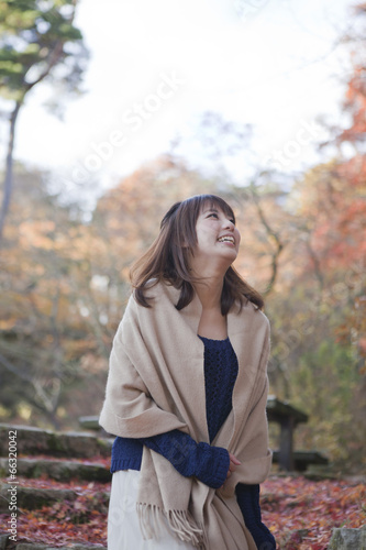 秋の紅葉の落ち葉の上の階段を歩く笑顔の女性