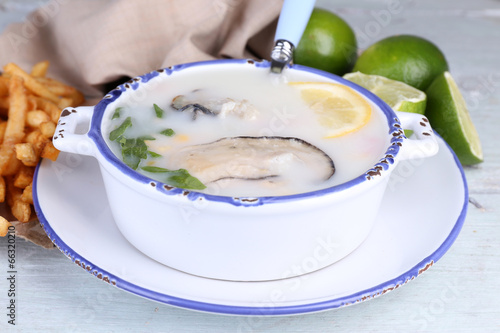 Tasty soup with oysters on wooden table photo