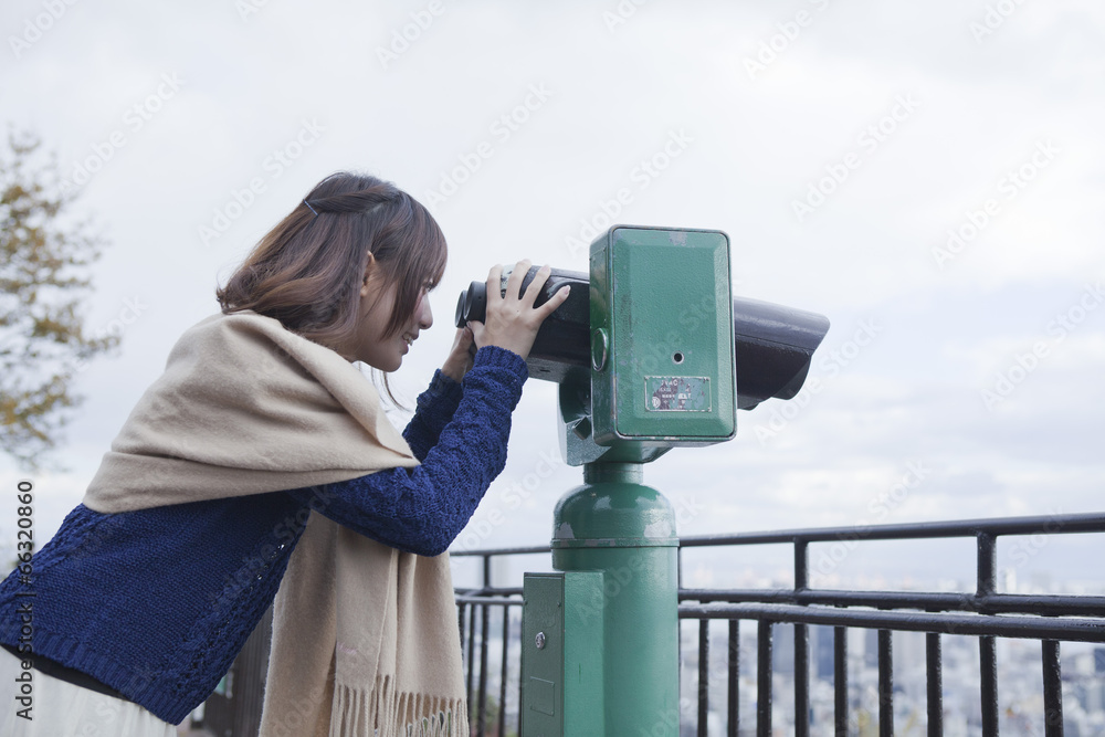 展望台から双眼鏡で神戸の景色を望む笑顔の女性