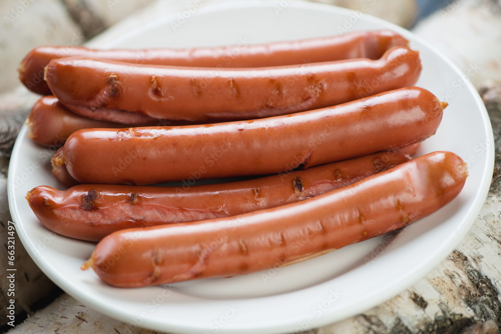 Glass plate with grilled sausages, horizontal shot, close-up Glass plate with grilled sausages, horizontal shot, close-up