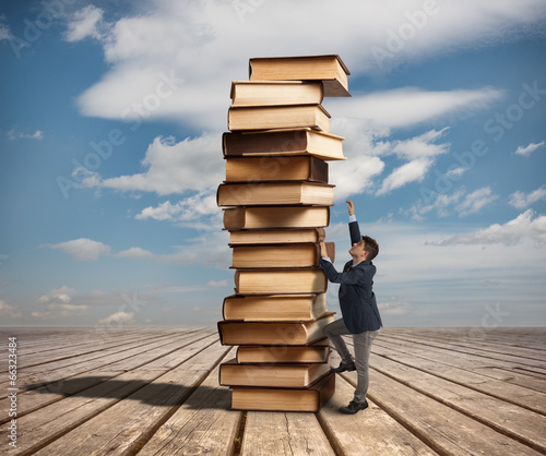 Man climbing a stack of books photo