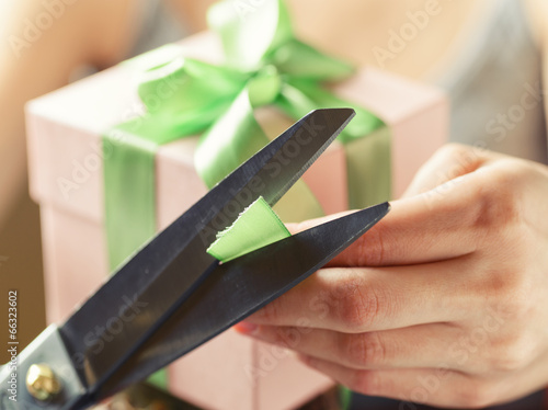 Decorating gift box with green ribbon using scissor