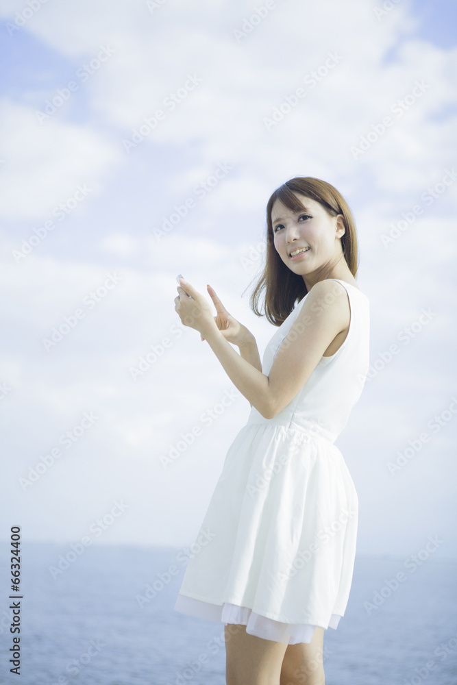 海辺で携帯を操作する女性 海辺で携帯を操作する女性