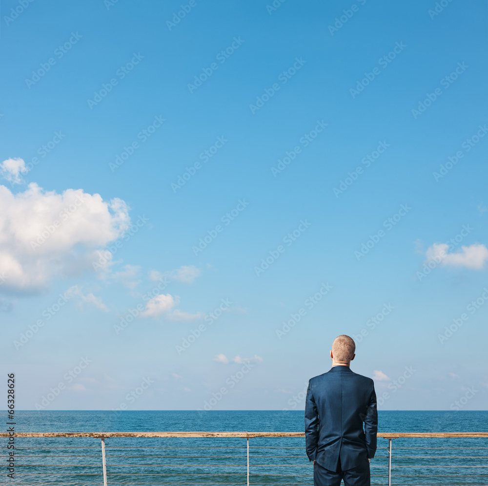 Businessman standing on a roof and looking at the ocean Businessman standing on a roof and looking at the ocean