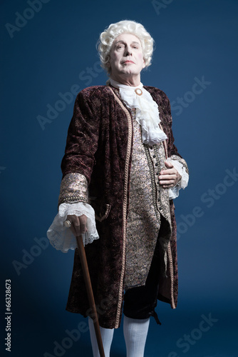 Retro baroque man with white wig standing with walking stick arr