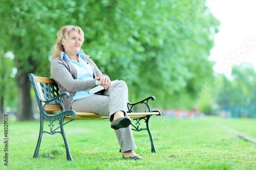 Mature lady relaxing in a park seated on a bench
