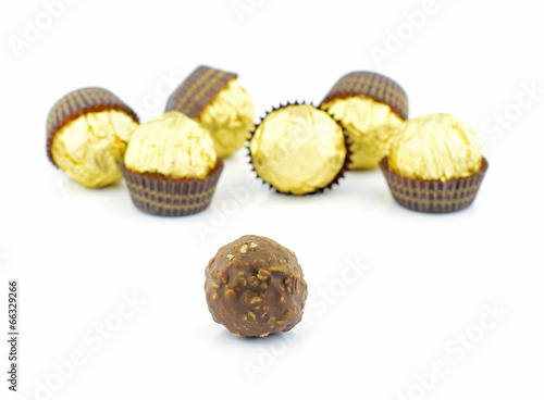 chocolate balls with almond in a gold foil paper on white backgr