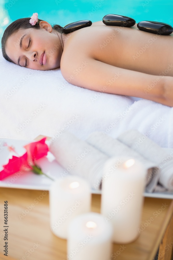 Smiling brunette lying on towel having a hot stone massage Smiling brunette lying on towel having a hot stone massage