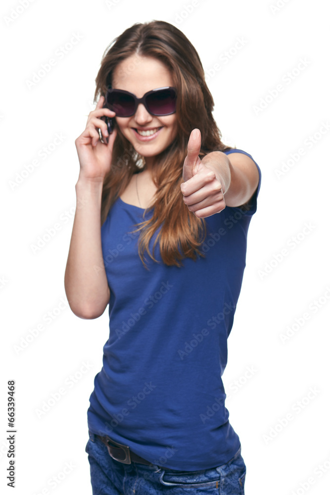 Smiling woman gesturing thumb up while talking on cell phone Smiling woman gesturing thumb up while talking on cell phone