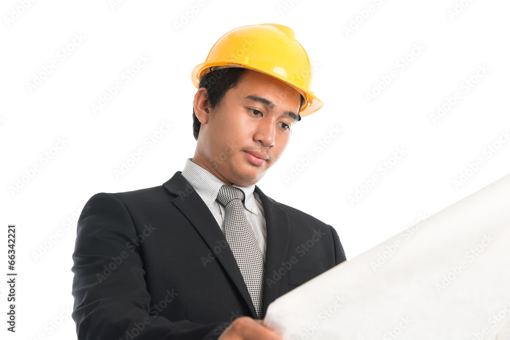 Asian male wearing yellow hardhat looking blue print paper. Asian male wearing yellow hardhat looking blue print paper.