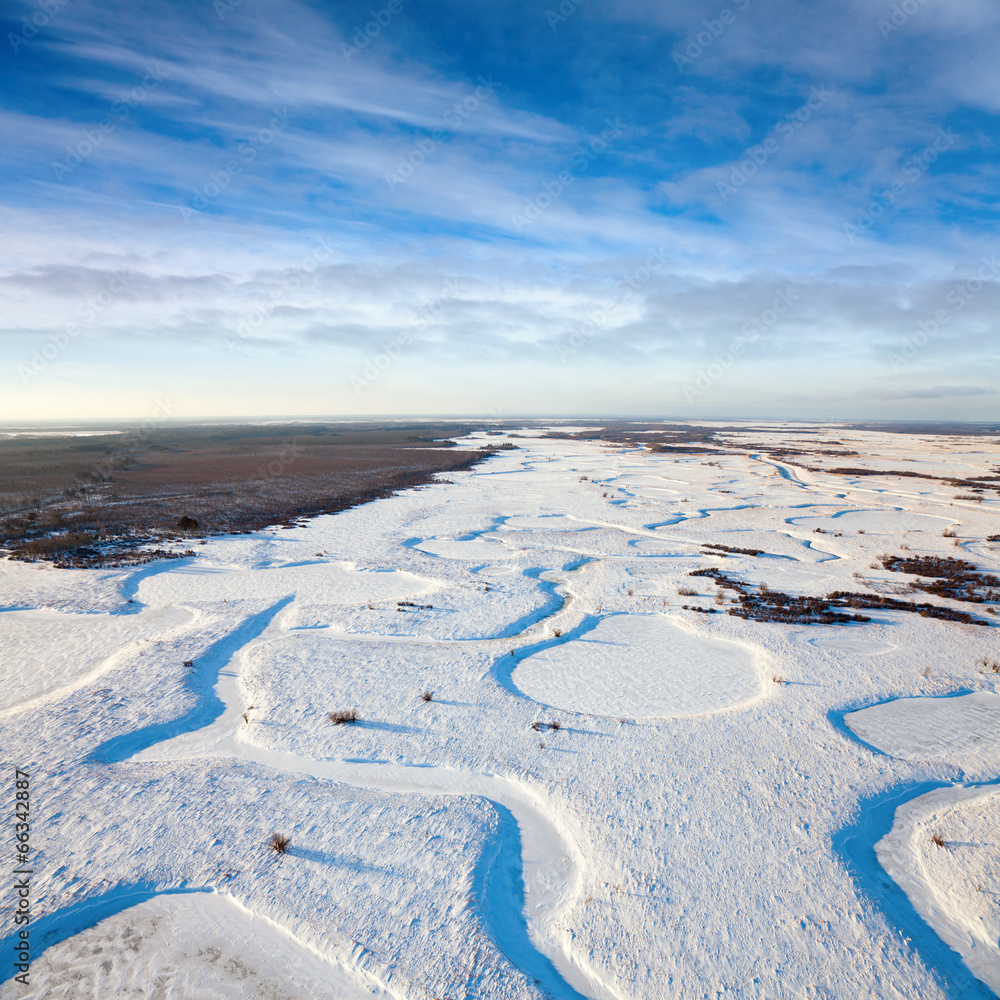 Top view of the snow-covered lowland of the forest river Top view of the snow-covered lowland of the forest river