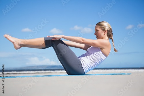 Focused fit blonde doing yoga on the beach