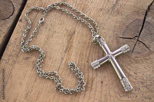 Silver christian cross with small diamonds on wooden background photo