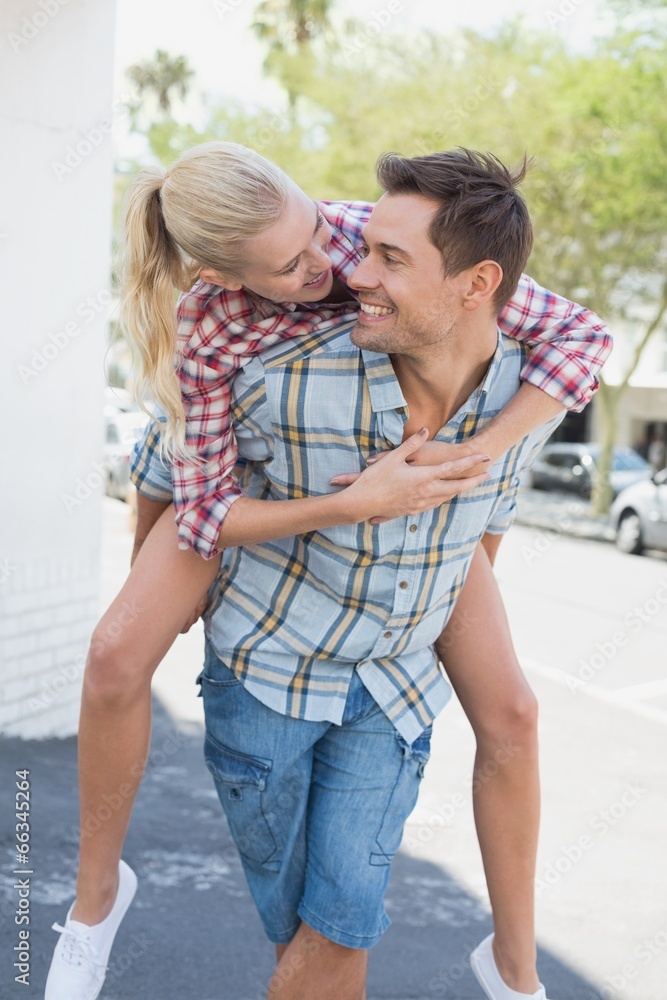 Naklejka premium Young hip man giving his blonde girlfriend a piggy back