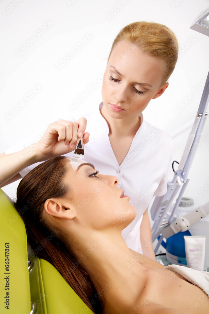 young woman getting beauty skin mask treatment on her face with young woman getting beauty skin mask treatment on her face with