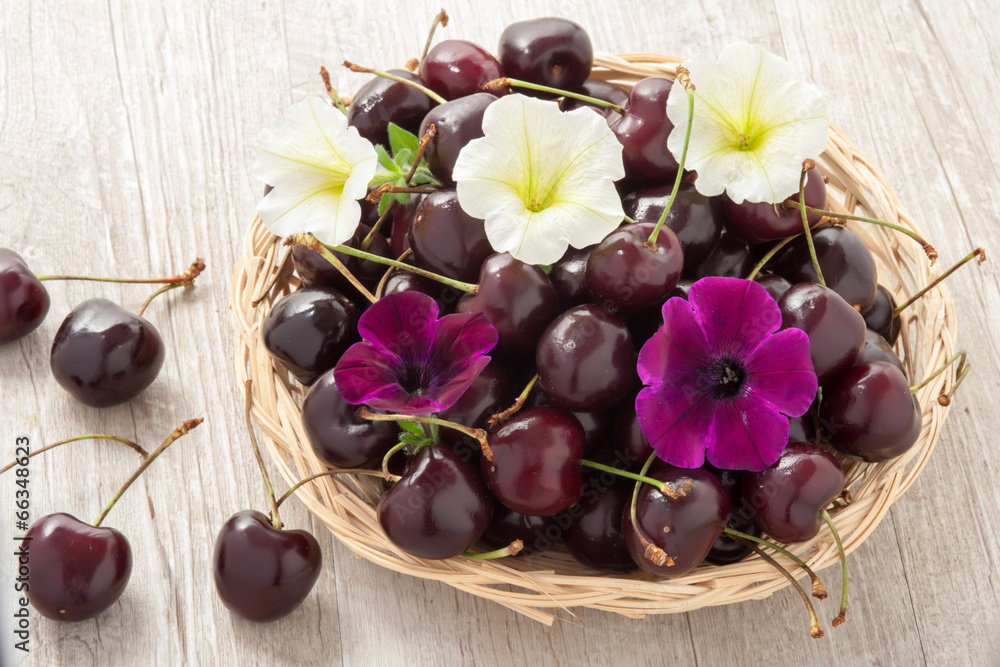 Cestino in vimini con ciliegie e fiori freschi Stock Photo