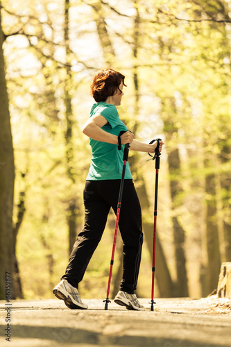 Nordic walking. Woman hiking in the forest park.