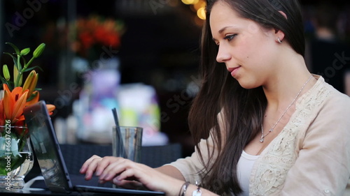 Wallpaper Mural Young woman typing on laptop in cafe Torontodigital.ca
