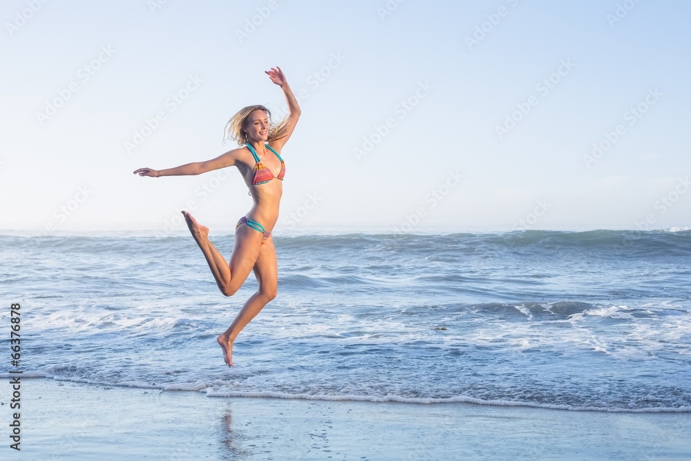 Happy blonde leaping on the beach in bikini Happy blonde leaping on the beach in bikini
