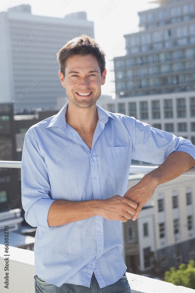Handsome man smiling at camera on his balcony Handsome man smiling at camera on his balcony