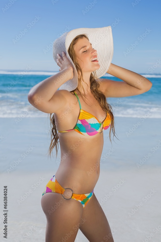 Beautiful girl in bikini and straw hat on the beach