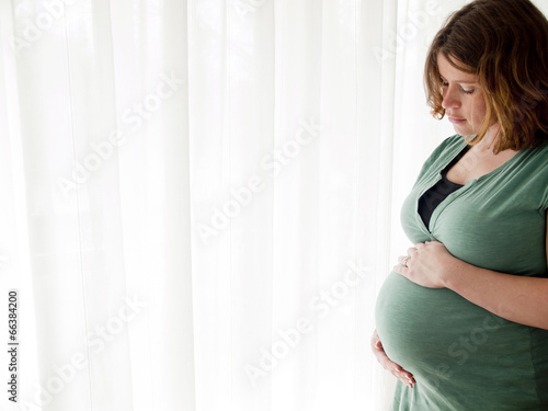 Pregnant young woman looking at her belly Free Download Pregnant young woman looking at her belly - GFXLoad