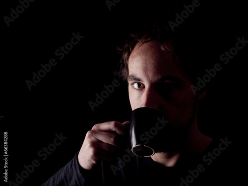 Low key image of a bearded man drinking coffee