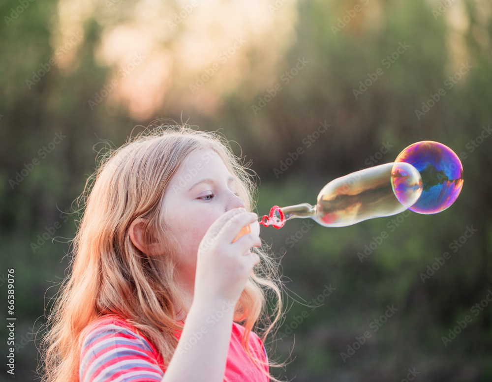 girl blowing soap bubbles outdoor at sunset