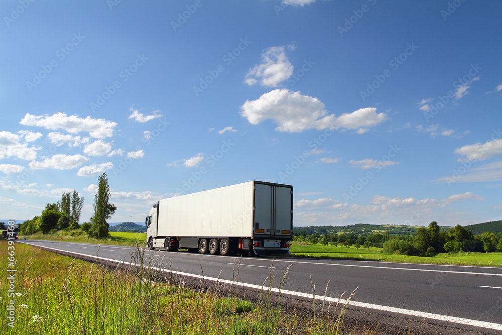 White truck driving through autumn landscape White truck driving through autumn landscape