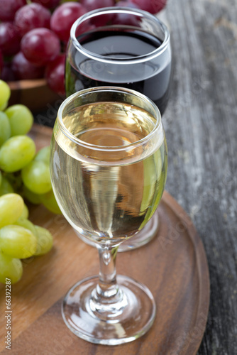 glass of white and red wine, fresh grapes on a wooden board