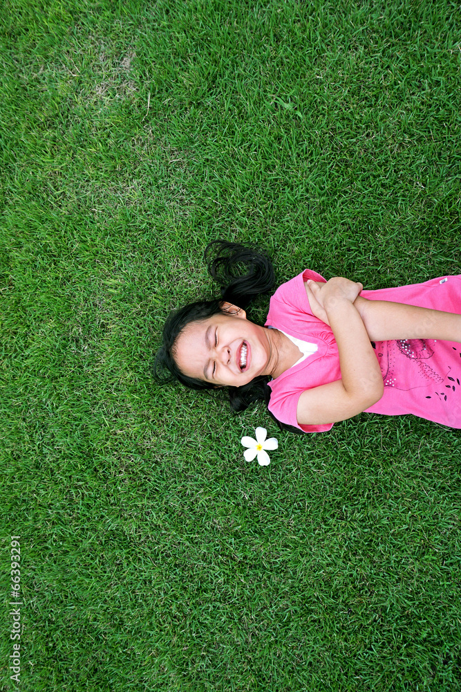 Little asian girl laying in green grass with frangipani flower Little asian girl laying in green grass with frangipani flower