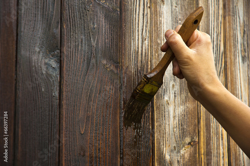 hand with paintbrush on wood