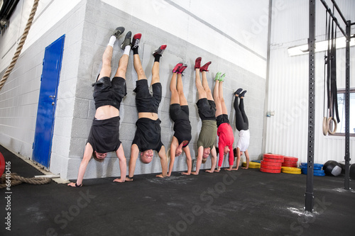 Fotografia Team exercising handstands at fitness gym center