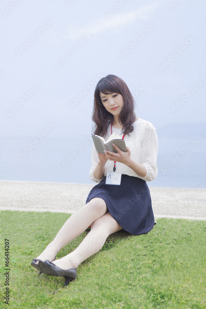 芝生に座って本を読む女性