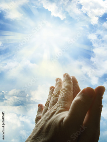 Prayer hands in bright heaven sky