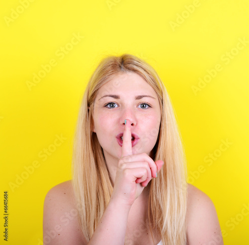 Cuadro en lienzo Portrait of girl with gesture for silence against yellow backgro