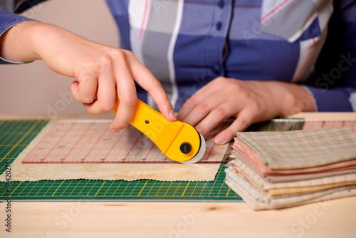 Close-up female hands cutting fabric with rotating cutter