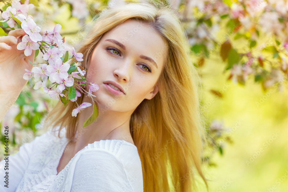 Beautiful girl in spring apple tree blossoms