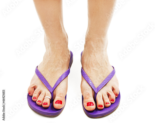 Female legs with flip-flops on white background